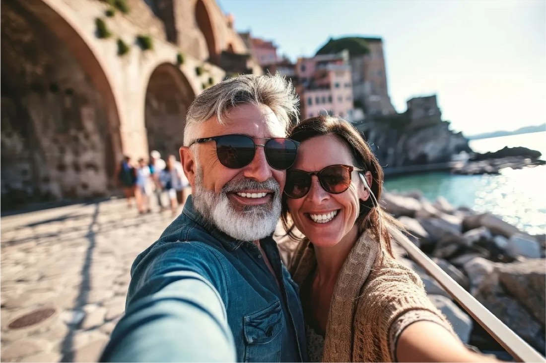 A smiling mature couple taking a selfie in a seaside Italian town